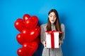Valentines day. Image of beautiful girl looking surprised at gift box, receive present from lover, standing in dress on