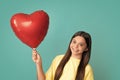 Valentines day and kids concept. Teenage girl in yellow dress with red heart-shaped balloon over blue background. Happy Royalty Free Stock Photo