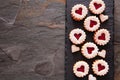 Valentines Day linzer jam cookies with heart shapes, side border on a slate serving platter with copy space