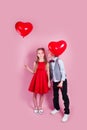 Valentines day. Little boy kissing beautiful little girl on pink background. Children holding heart balloons Royalty Free Stock Photo