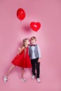 Valentines day. Little girl kissing boy on pink studio background. Children with heart balloons Royalty Free Stock Photo