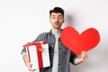 Valentines day and love concept. Guy waiting for kiss, bring lovely gifts and red heart card, pucker lips and look at