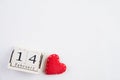 Valentines day and love concept. Handmade red heart and February 14 text on wooden block on white wooden background