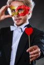 Man in carnival mask with heart stick love symbol