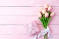 Pink paper hearts with gift box and tulips with ribbon on pink pastel wooden background Royalty Free Stock Photo