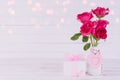 Valentines day and love concept. Pink roses in vase with wooden heart and gift box on white wooden background Royalty Free Stock Photo