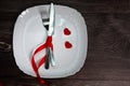 Valentines day meal background with red ribbon, hearts, fork, knife, white plate and napkin. Romantic holiday table Royalty Free Stock Photo