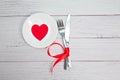 Valentines day meal background with red ribbon, hearts, fork, knife, white plate and napkin. Romantic holiday table Royalty Free Stock Photo