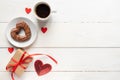 Valentines day mockup. Coffee, heart shaped chocolate cookie, gift box and paper card with craft envelope on white wooden table Royalty Free Stock Photo