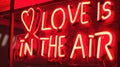 Valentines Day Neon vibrant red sign with phrase LOVE IS IN THE AIR and hearts