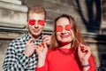 Valentines day photo booth props. Man and woman hiding eyes behind red hearts. Couple having fun Royalty Free Stock Photo