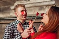 Valentines day photo booth props. Man and woman hiding eyes behind red hearts. Couple in love having fun Royalty Free Stock Photo