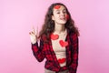 Valentines Day. Portrait of playful cute teen girl with heart stickers on her face and clothes. studio shot, pink background