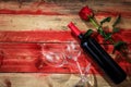 Valentines day. Red wine bottle, glasses and a rose on red wooden background Royalty Free Stock Photo