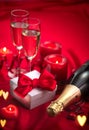 Valentines Day romantic dinner. Date. Champagne, candles and gift box over holiday red background