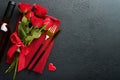 Valentines day romantic table setting. Empty closeup of red roses, wine, candles, dinner black plate, knife, fork and decorative Royalty Free Stock Photo