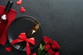 Valentines day romantic table setting. Empty closeup of red roses, wine, candles, dinner black plate, knife, fork and decorative Royalty Free Stock Photo