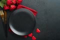 Valentines day romantic table setting. Empty closeup of red roses, wine, candles, dinner black plate, knife, fork and decorative Royalty Free Stock Photo