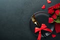 Valentines day romantic table setting. Empty closeup of red roses, wine, candles, dinner black plate, knife, fork and decorative Royalty Free Stock Photo