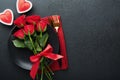 Valentines day romantic table setting. Empty closeup of red roses, wine, candles, dinner black plate, knife, fork and decorative Royalty Free Stock Photo