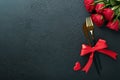 Valentines day romantic table setting. Empty closeup of red roses, wine, candles, dinner black plate, knife, fork and decorative Royalty Free Stock Photo