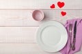 Valentines day romantic table setting, red tape, paper hearts tea cup, plate, silverware, pink napkin on white wooden Royalty Free Stock Photo