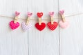 Valentines Day. Sewed pillow hearts row border on red and white clothespins at rustic white wood planks. Royalty Free Stock Photo