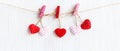 Valentines Day. Sewed pillow hearts row border on red and white clothespins at rustic white wood planks. Royalty Free Stock Photo