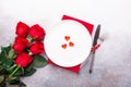 Valentines day table place setting with bouquet of roses, red hearts and silverware on stone background. Top view. Valentine`s Royalty Free Stock Photo