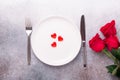 Valentines day table place setting with bouquet of roses, red hearts and silverware on stone background. Top view. Valentine`s Royalty Free Stock Photo