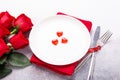 Valentines day table place setting with bouquet of roses, red hearts and silverware on stone background. Valentine`s card Royalty Free Stock Photo