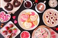 Valentines Day table scene with assorted sweets and cookies, above view over a dark background