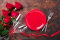 Valentines day table setting empty plate, red roses and champagne glasses on wooden background. Top view. Valentine`s greeting Royalty Free Stock Photo