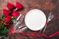 Valentines day table setting empty plate, red roses and champagne glasses on wooden background. Top view. Valentine`s greeting Royalty Free Stock Photo