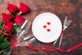 Valentines day table setting empty plate, red roses and champagne glasses on wooden background. Top view. Valentine`s greeting Royalty Free Stock Photo