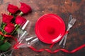 Valentines day table setting empty plate, red roses, velvet ring box and champagne glasses on wooden background. Top view. Royalty Free Stock Photo