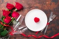 Valentines day table setting empty plate, red roses, velvet ring box and champagne glasses on wooden background. Top view. Royalty Free Stock Photo