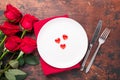 Valentines day table setting empty plate and red roses on wooden background. Top view. Valentine`s greeting card Royalty Free Stock Photo