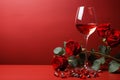 Valentines dining concept Red roses and an empty red wine glass on a red background Royalty Free Stock Photo