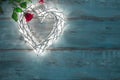 Valentines illuminations in the shape of a heart on a wooden background and red rose. Royalty Free Stock Photo