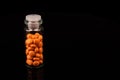 Valerian in a bottle on a black background, mirroring. Space for text. Royalty Free Stock Photo