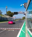 Race car crossing finish line under waving checkered flag Royalty Free Stock Photo