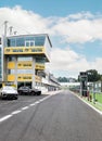 Motor sport circuit empty pit lane front view, wall and control building blue cloudy sky