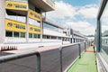 Motor sport circuit empty pit lane front view, wall and control building blue cloudy sky