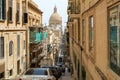 Typical Valletta street architecture with traditional Maltese rising road, wooden enclosed balconies and a dome of Basilica of Our