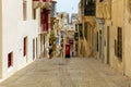 Typical Valletta street architecture with traditional Maltese wooden enclosed balconies, sloping down road and a red mailbox