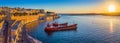 Valletta, Malta - Panoramic skyline view of Valletta and the Grand Harbor with beautiful sunrise, ships and clear blue sky