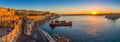 Valletta, Malta - Panoramic skyline view of Valletta and the Grand Harbor with beautiful sunrise, ships and clear blue sky