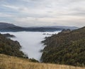 Valley in the autumn Caucasus mountains with fog below and rocky slopes overgrown with trees and vegetation in autumn Royalty Free Stock Photo