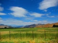 Valley with green grass, mountains in the distance blue sky with whispy clouds